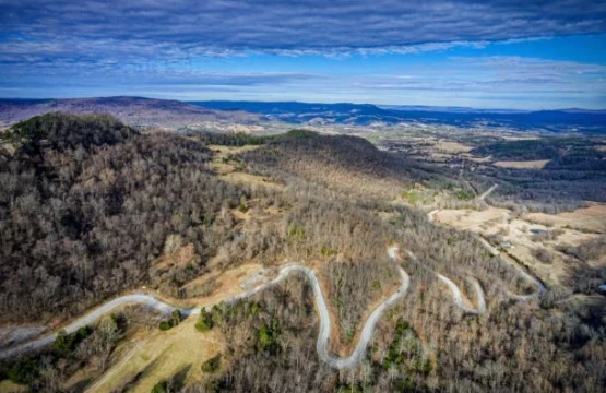 Aerial view of a winding mountain road through wooded hills