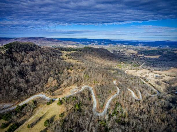 Aerial view of a winding mountain road through wooded hills