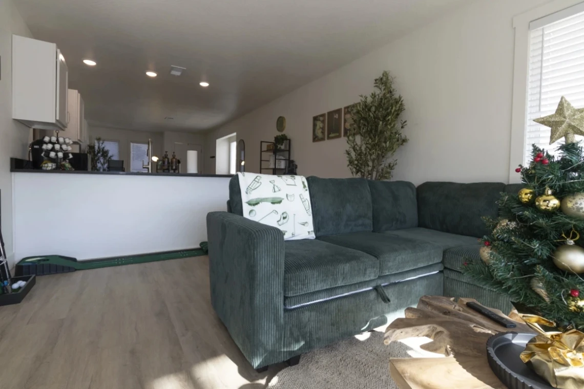 Condo living area with green sectional, Christmas tree and kitchen bar