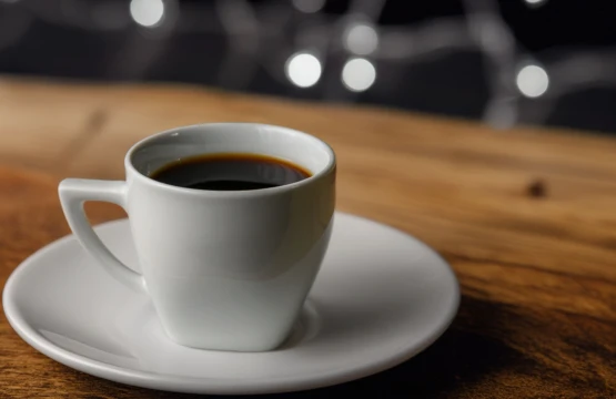 White cup of black coffee on a saucer on a wooden table