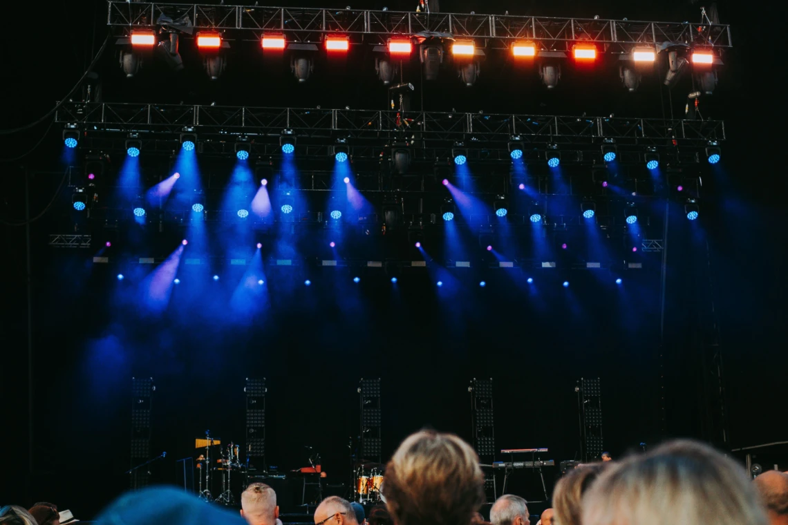 Concert stage with blue spotlights and audience in the foreground