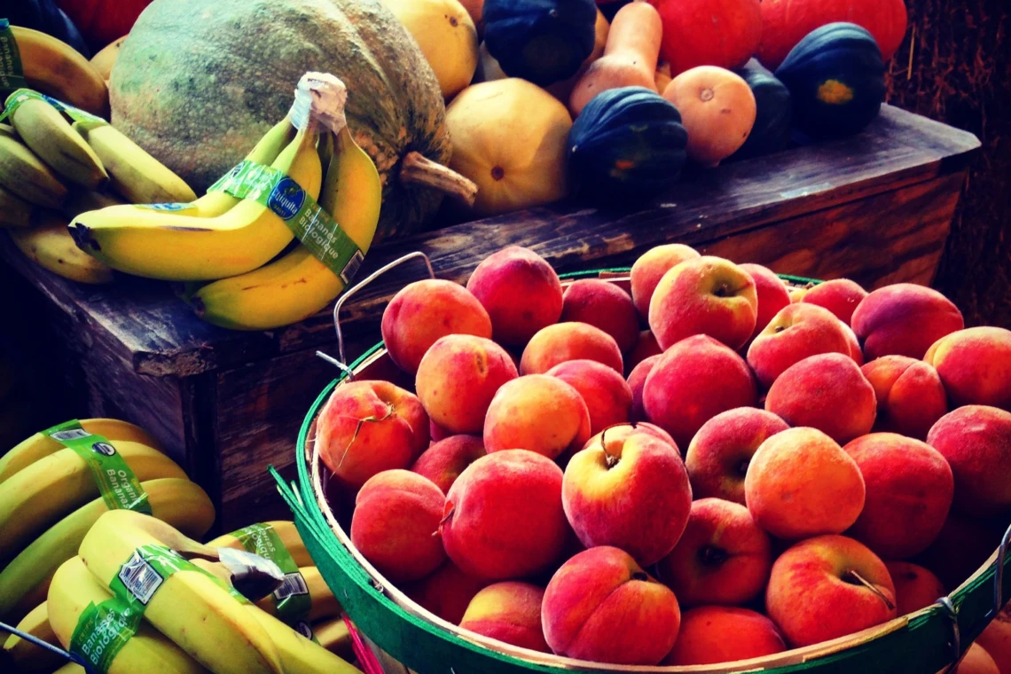 Baskets of apples, pumpkins, squash and bananas at a market stand