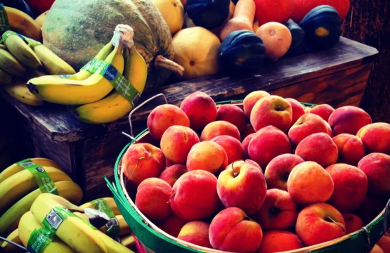 Baskets of apples, pumpkins, squash and bananas at a market stand