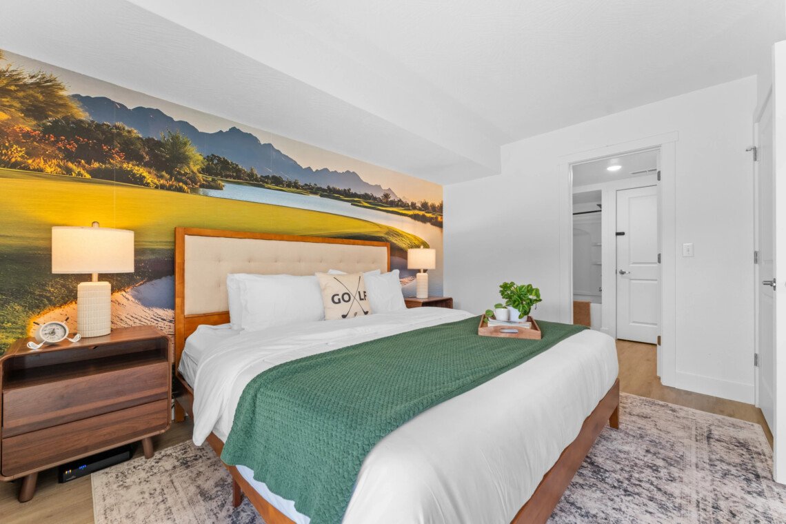 Cozy king bedroom with golf course mural, green throw and nightstand lamps